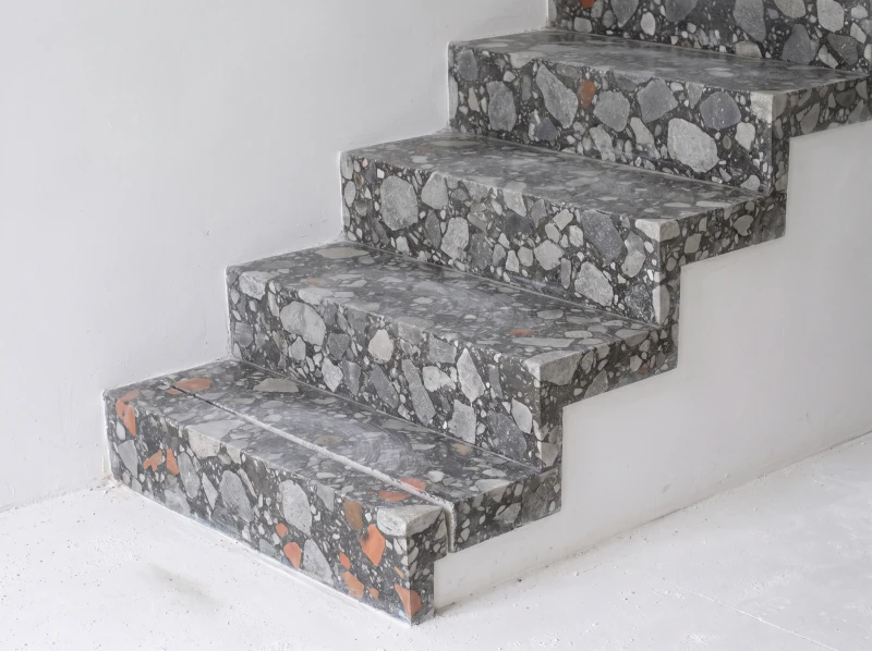 Stair treads cut from coarse grey stone terrazzo in a dark cement