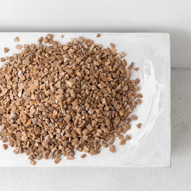 Loose warm brown marble chip heaped on a chalk surface