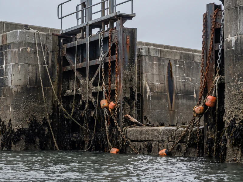 A tidal lock gate seen from the water with barnacles on the steel