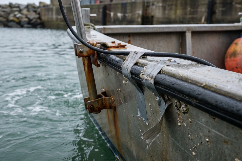 An echo sounder pole clamped to the gunwale of a workboat
