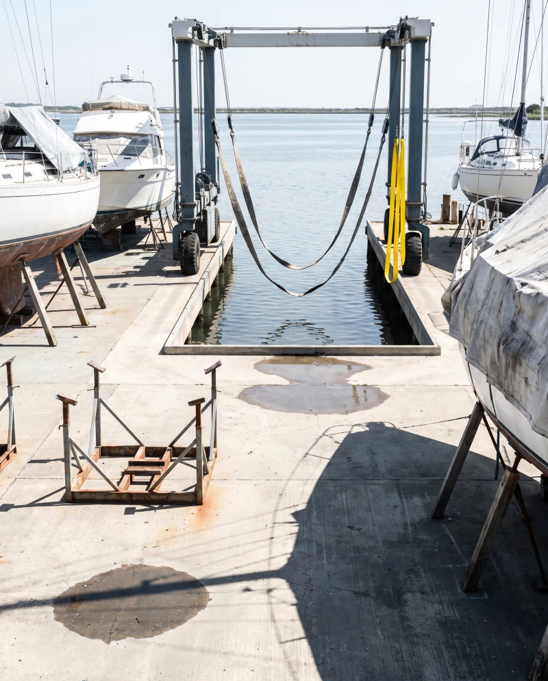 The slip at a rising tide, the hoist slings lowered to the water