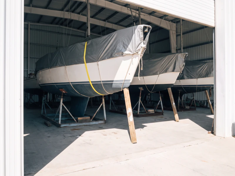 Covered boats on the hard under a shed roof, masts down